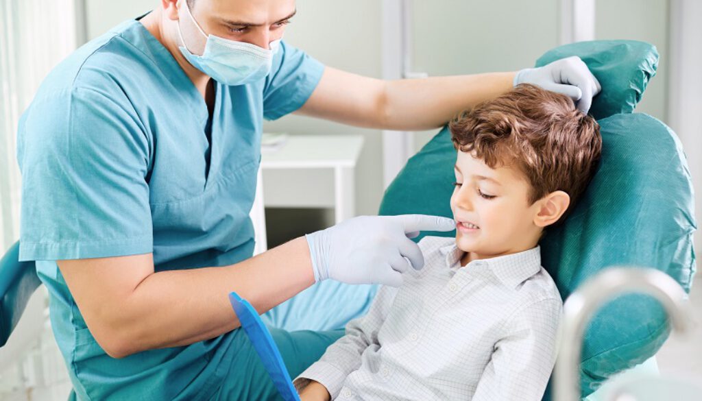 Boy child and dentist are checking teeth in the mirror.